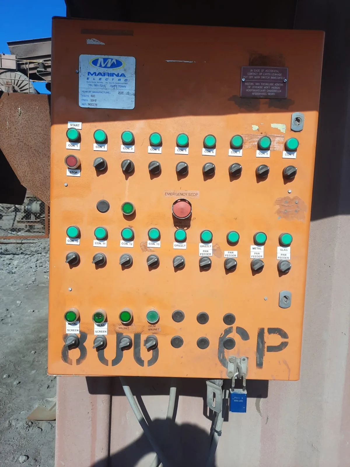 Orange industrial control panel with rows of labelled switches and indicator lights.