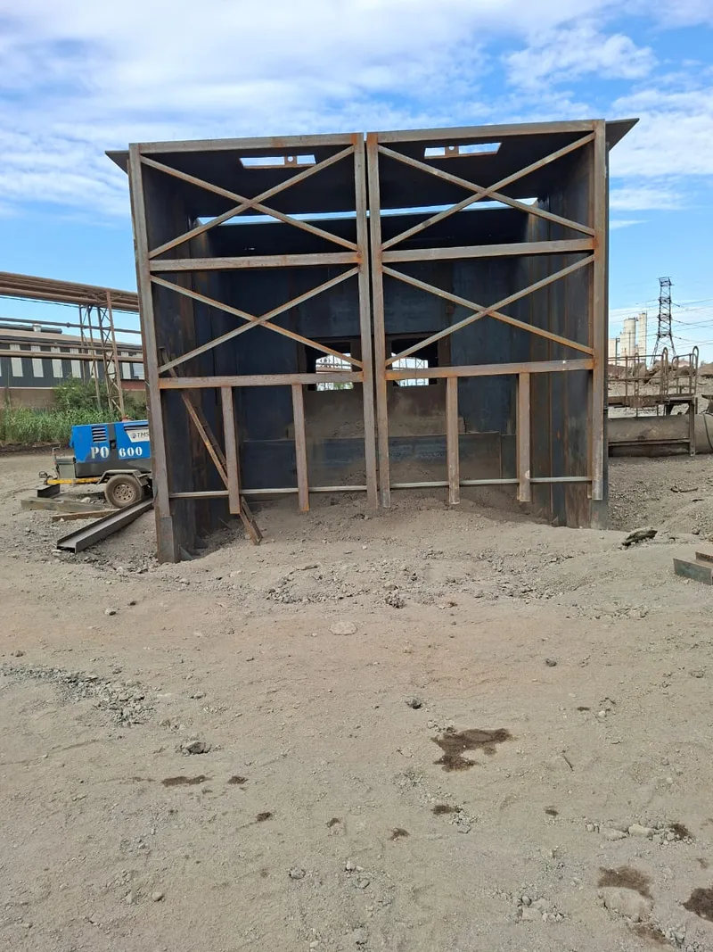 Steel cubicle structure with cross-bracing and panelled sides.