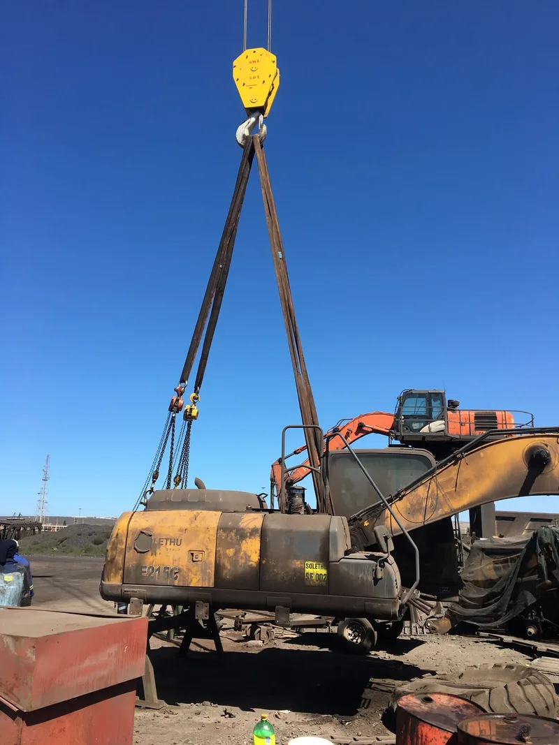 Crane hook, slings and chain tackle attached to excavator machinery.